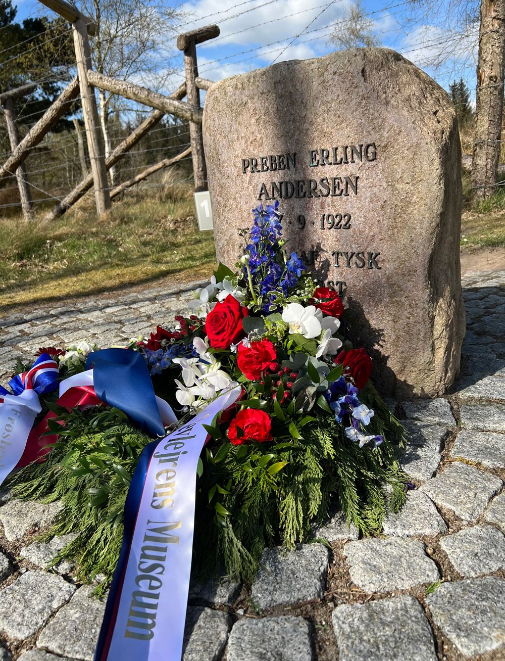 Memorial stone for Preben Erling Andersen from 1922 with wreaths and flowers by the barbed wire at Frøslev Camp