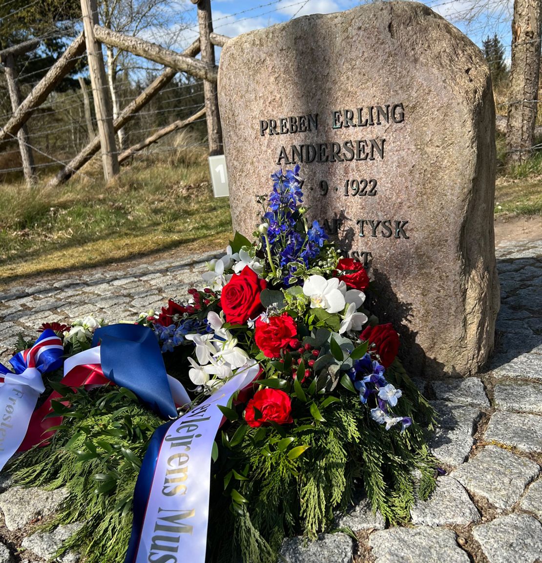 Memorial stone for Preben Erling Andersen from 1922 with wreaths and flowers by the barbed wire at Frøslev Camp