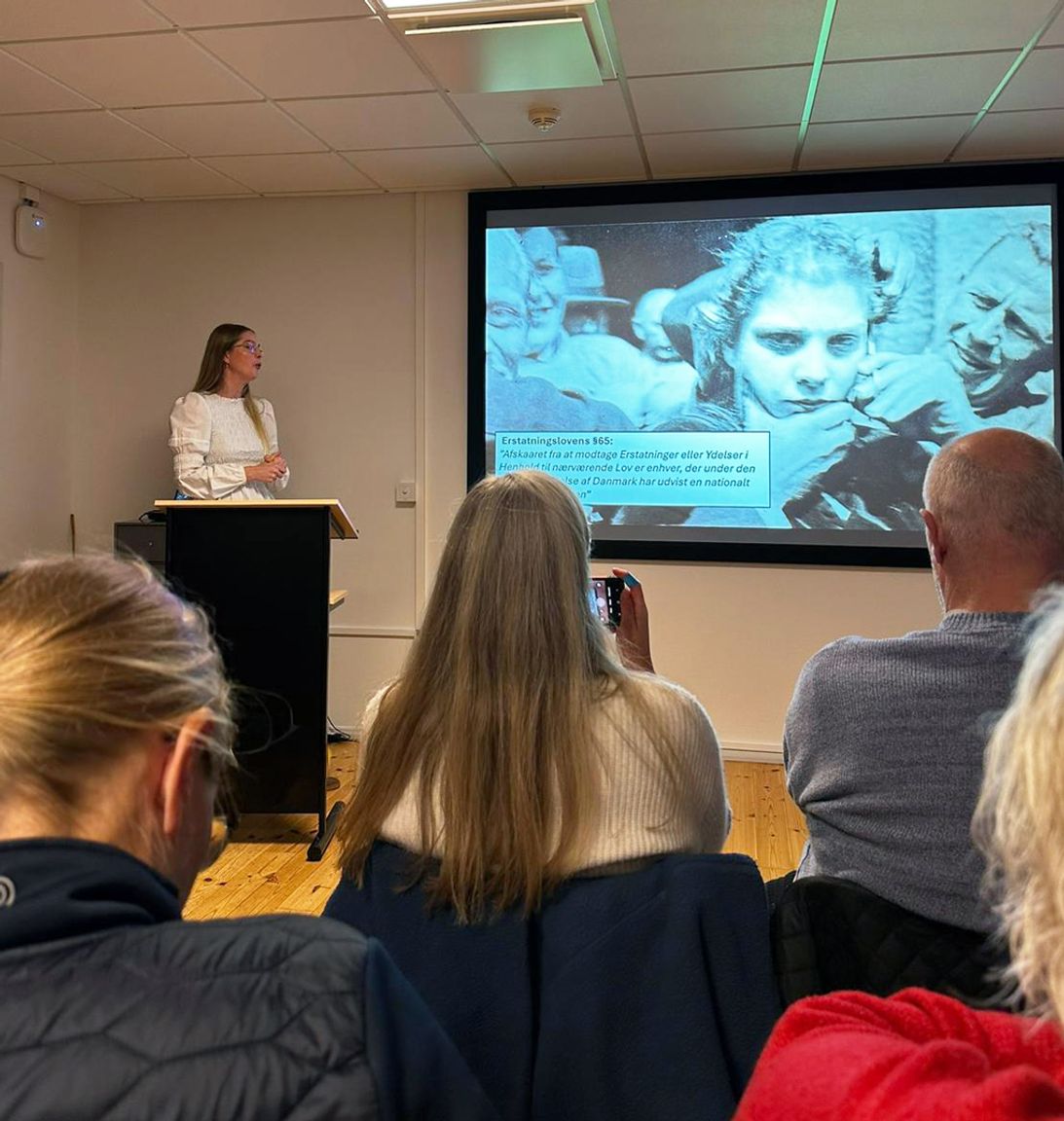 En gruppe hører et foredrag om Faarhuslejren i Frøslevlejren