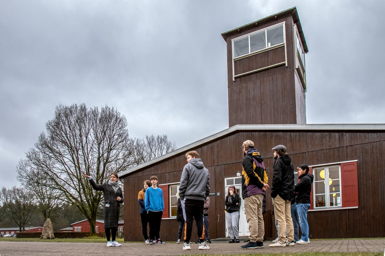 A group of students stands in front of the main guard tower at Frøslev Camp.