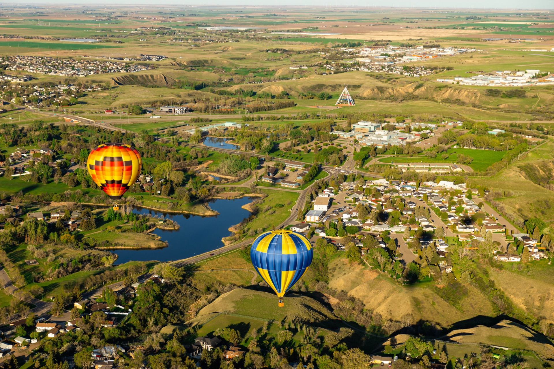 Two colourful hot air balloons fly over the coulees of Medicine Hat.