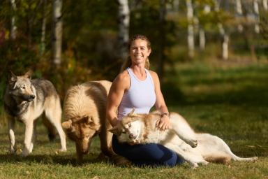 Georgina De Caigny, founder and owner of Yamnuska Wolfdog Sanctuary, poses with a pack of young wolfdogs.