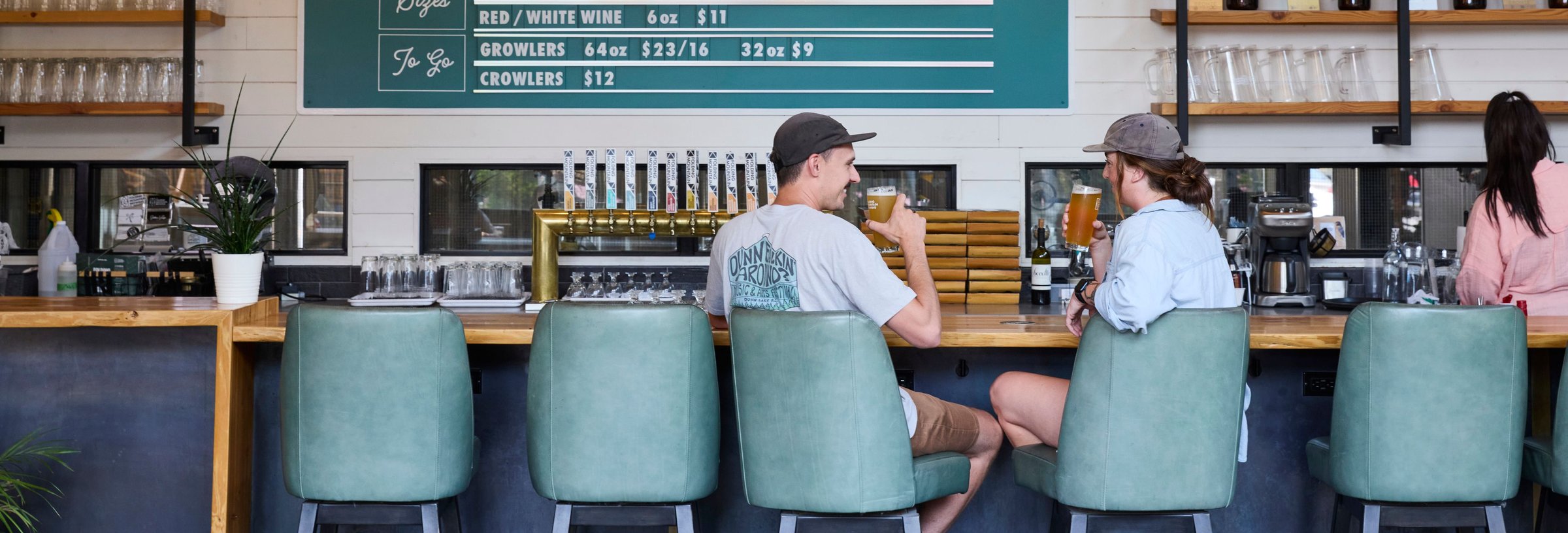 Two people sitting at the bar with a beverage.