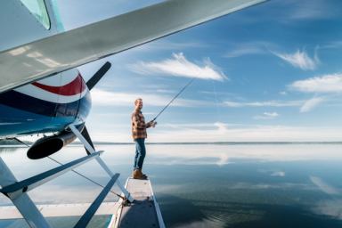 A man fishes off of a float plane.