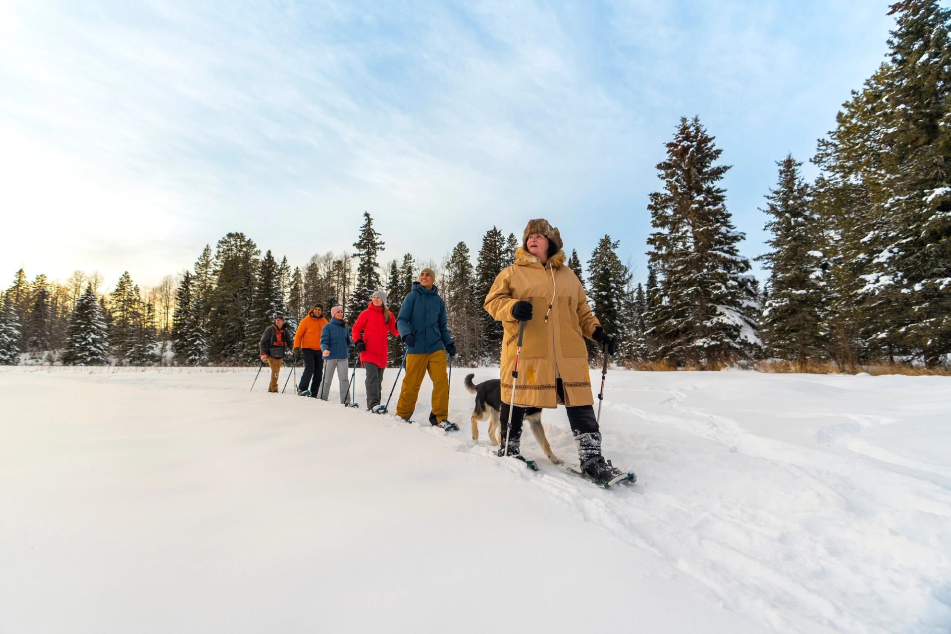 A group of people on a guided snowshoe walk across a lake.