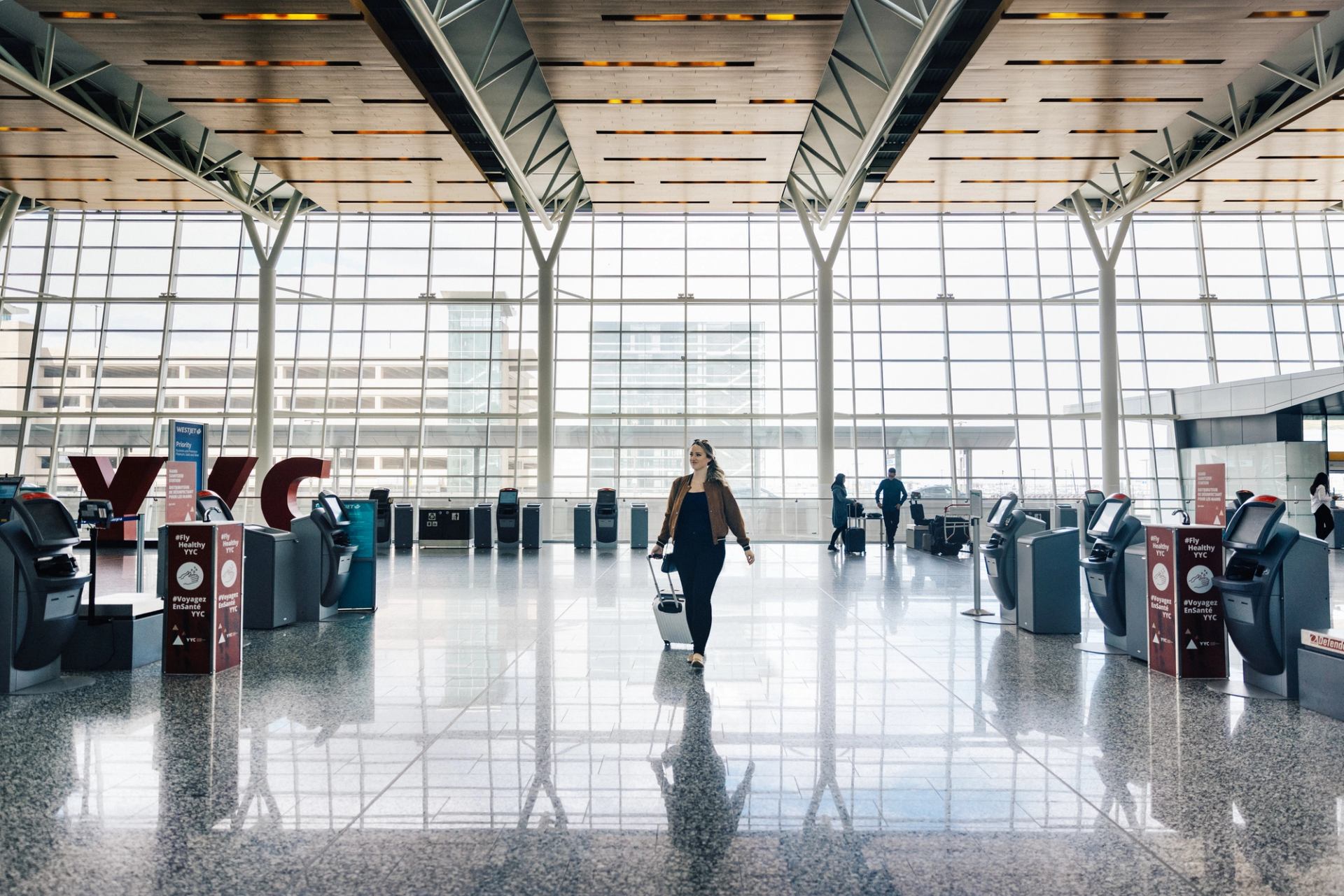 Woman walking with luggage through airport terminal