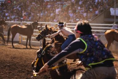 Two relay riders thunder toward the exchange zone, where teammates stand ready.