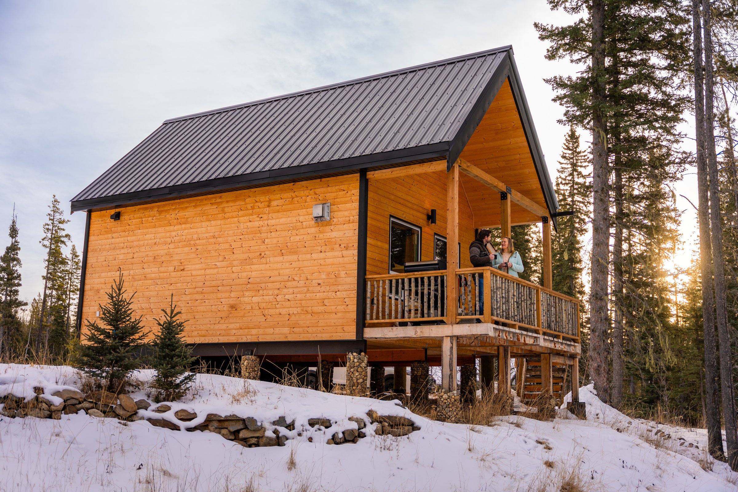 Couple enjoying a beverage on the deck of a cabin at Expanse Cottages