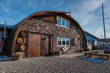 The stone and wood exterior of the Spirit Hills Winery, a Quonset hut-type building.