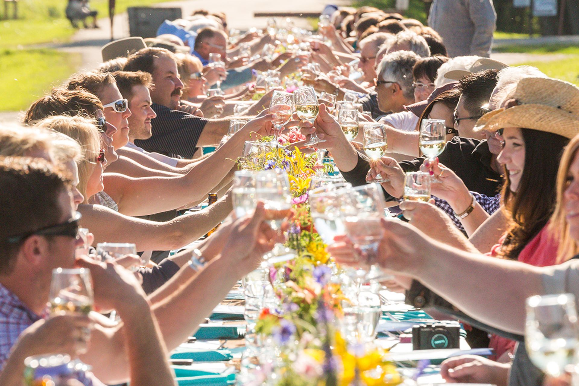 Group of people dining outdoors at a long table at the Taste of Markerville near Red Deer.