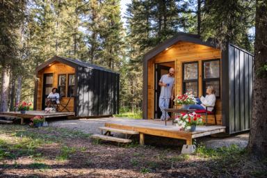 People relax on the porches outside their cabins in the forest.