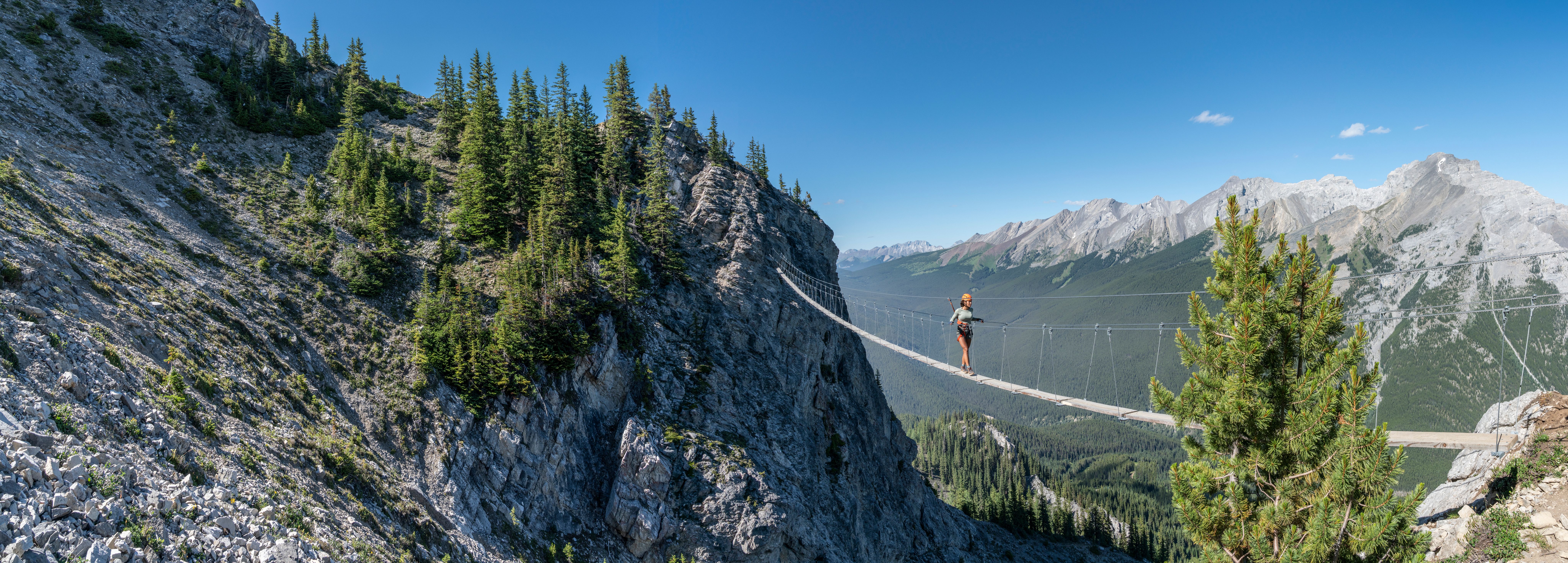 Person walking across a suspension bridge wearing climbing gear at Mount Norquay in Banff National Park.
