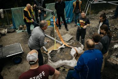 A paleontology team lifts a dinosaur skull fossil out of the earth at the Pipestone Creek Bonebed in Alberta.