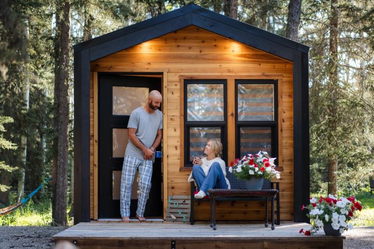 Guests relax on the porch of a modern mini cabin in the boreal forest.