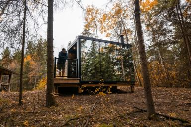 Man standing outside of cabin surrounded by the forest at Elk Island Retreat. 
