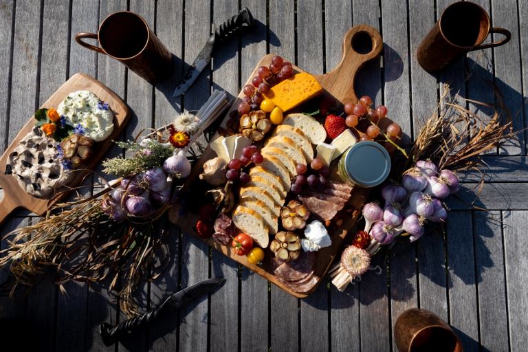 An artfully arranged charcuterie board on a picnic table.