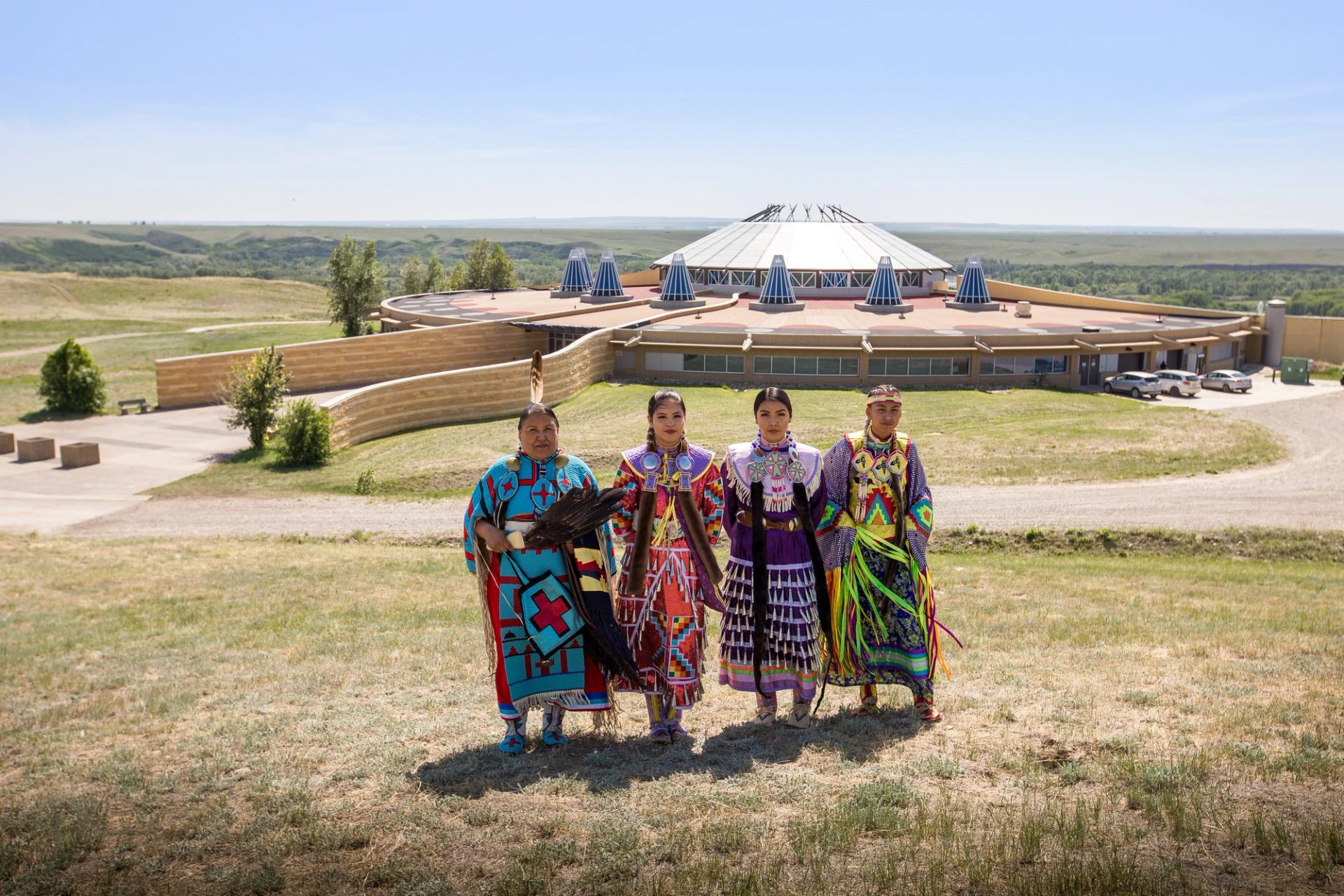 Siksika Blackfoot dancers standing in front of the Blackfoot Crossing Historical Park Interpretive Centre