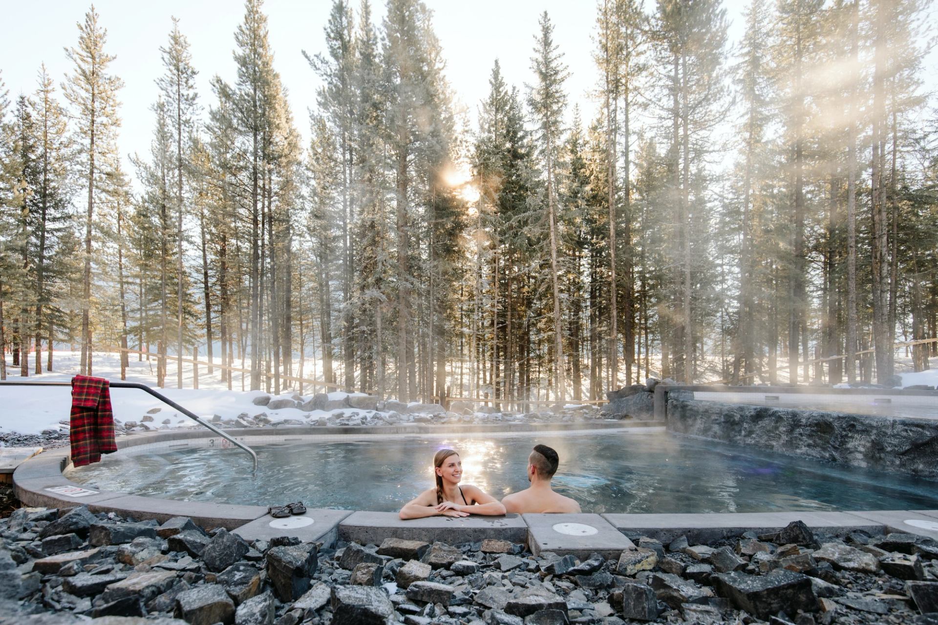 Snow scene with a couple in an outdoor hot tub at the Nordic Spa. Credit: Travel Alberta / Mike Seehagel