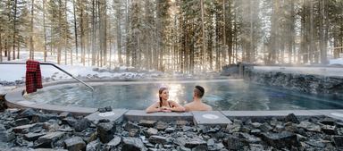 Snow scene with a couple in an outdoor hot tub at the Nordic Spa. Credit: Travel Alberta / Mike Seehagel