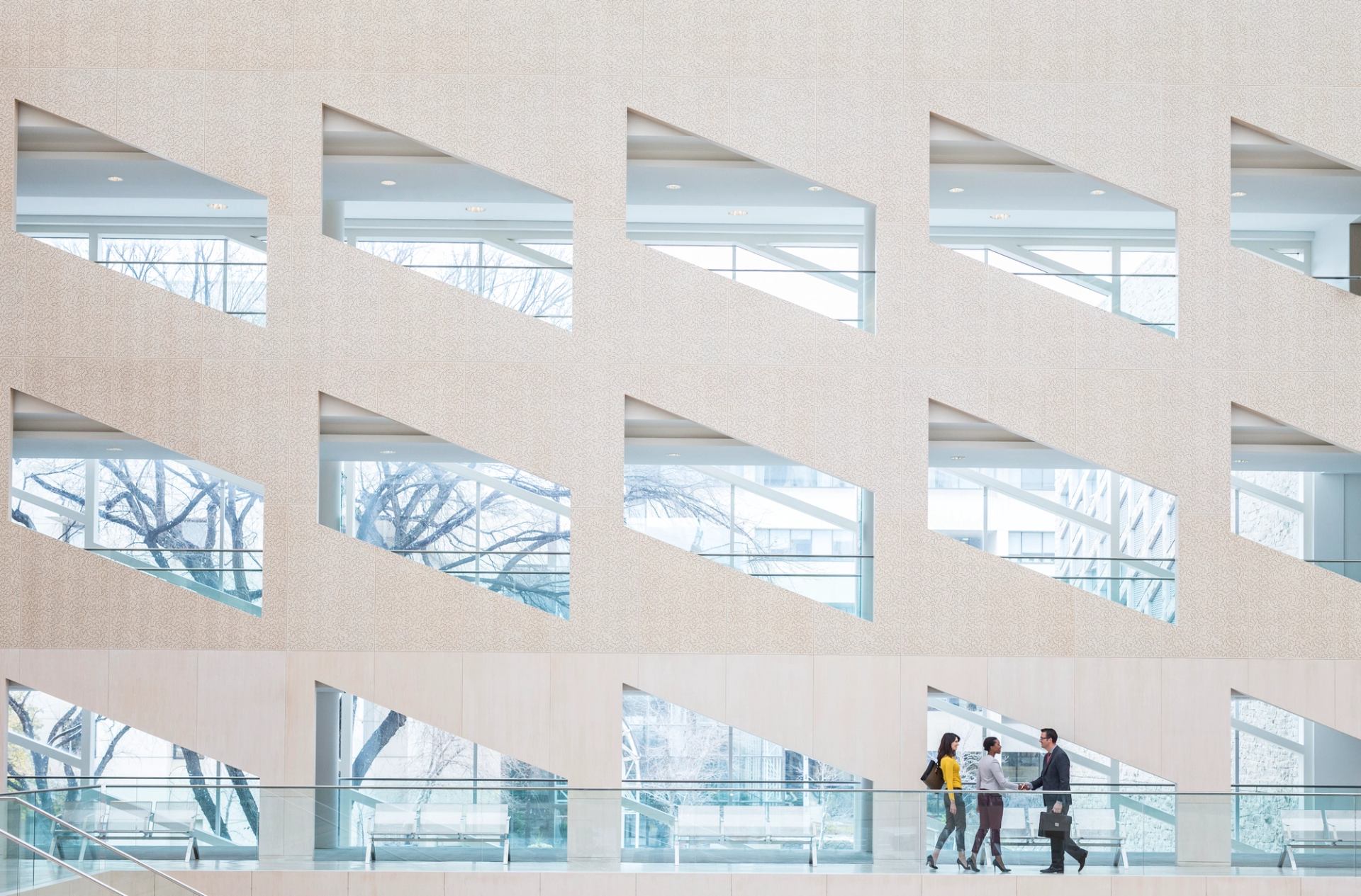 Three people in front of a wall of windows inside the Edmonton City Hall building.