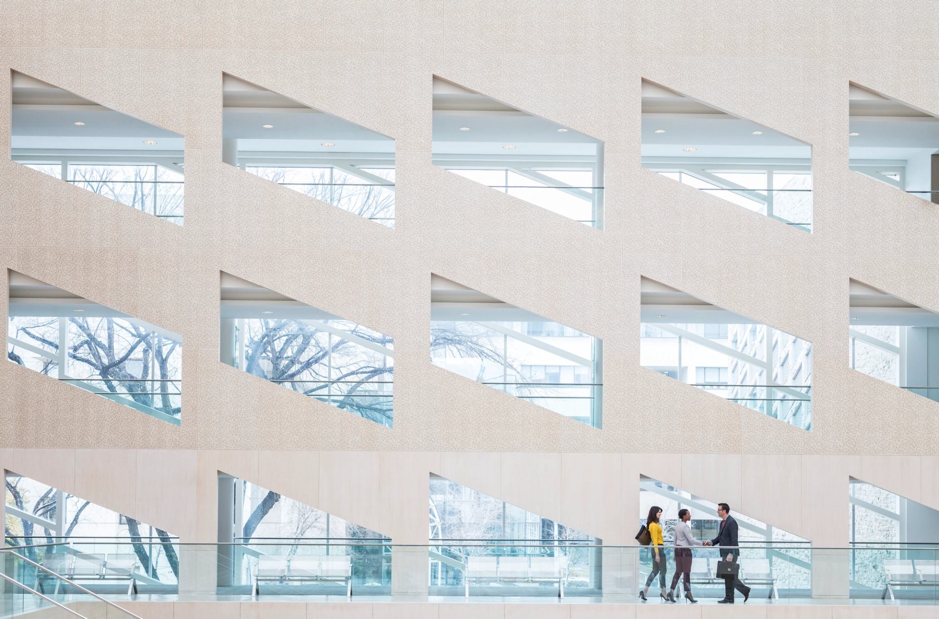 Three people in front of a wall of windows inside the Edmonton City Hall building.