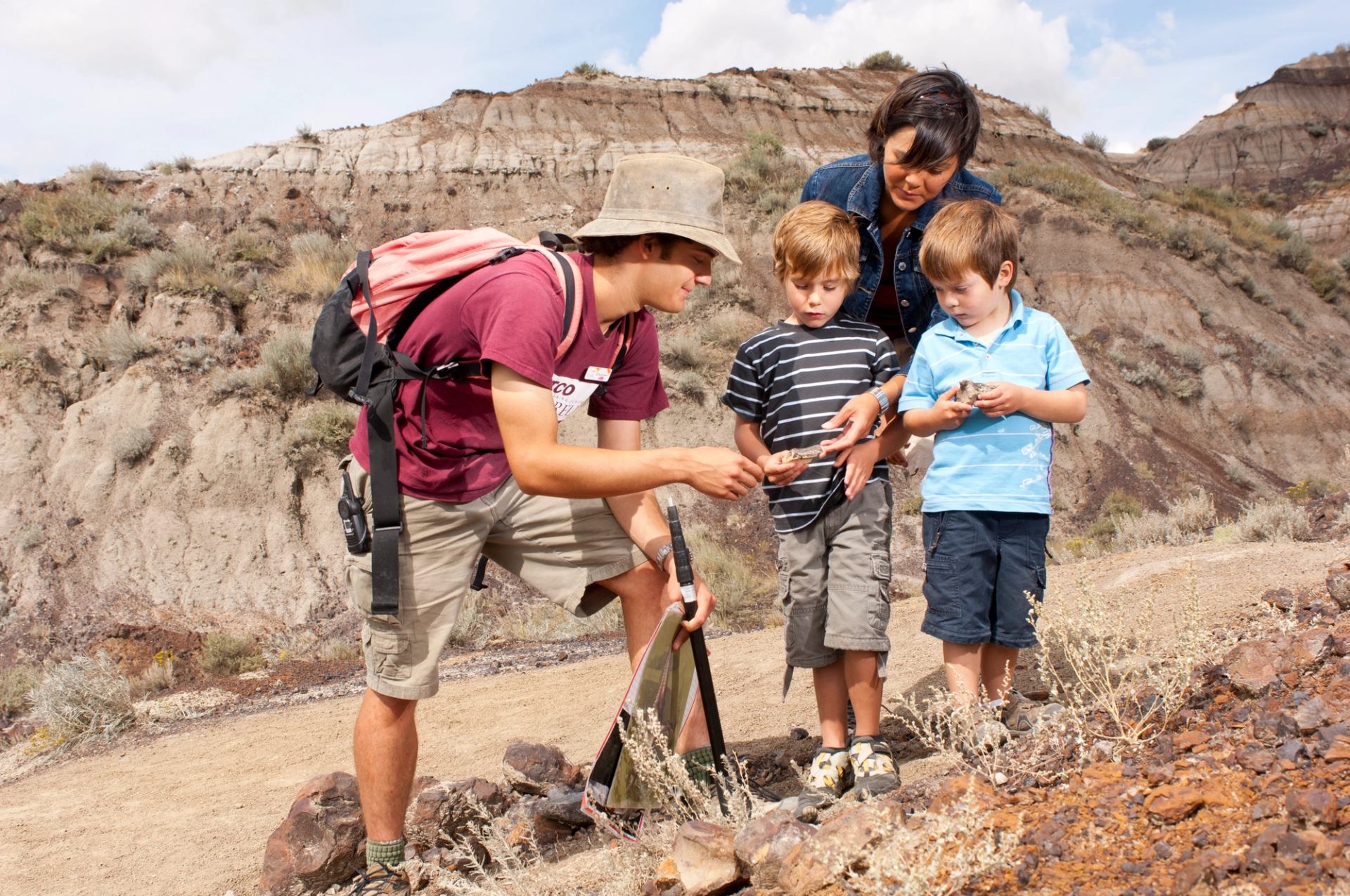 A tour guide showing a mother and two young children a fossil.