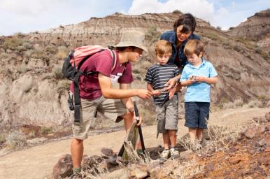 A guide in the Badlands shows two young kids an interesting artifact on a trail.