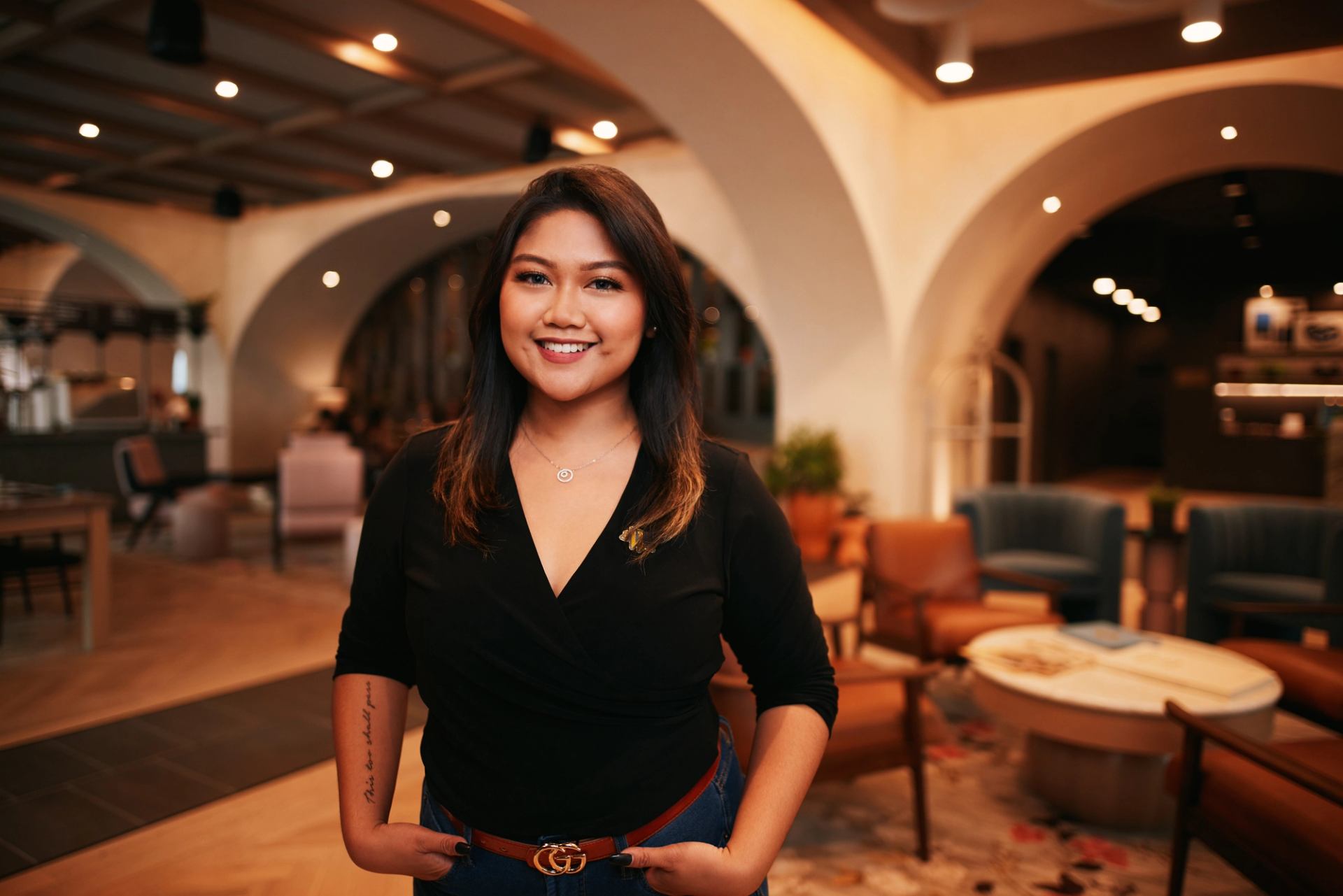 A smiling hotel agent stands in a contemporary hotel lobby.