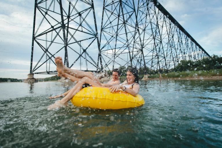 A young couple rafting on the Oldman River under a bridge near Lethbridge. 