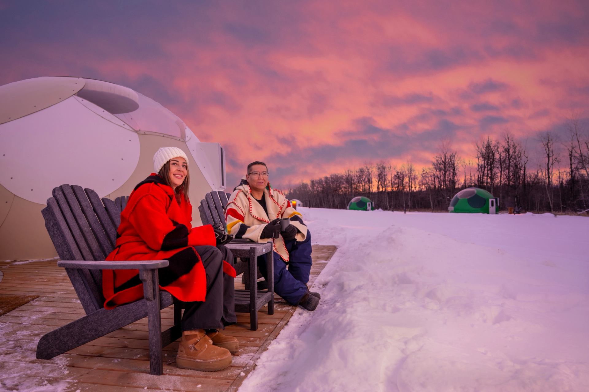 A couple enjoys sunset in front of a glamping dome at Métis Crossing.