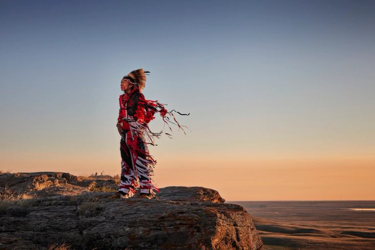 Man standing at the edge of a canyon wearing traditional clothing