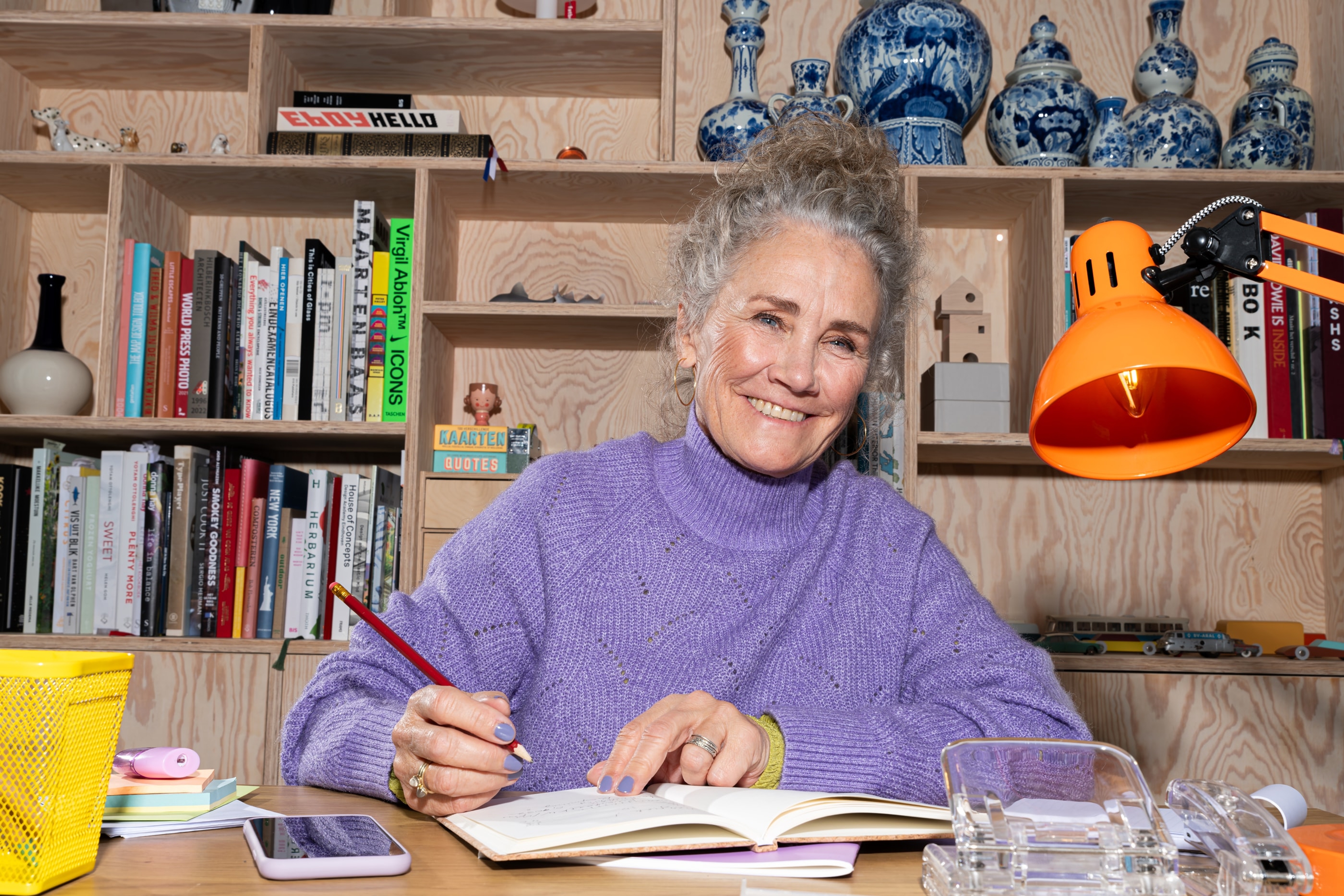 Een oudere warme vrouw met potlood schrijft aan bureau over haar energierekening, eenvoudig energiebeheer met Energiek.