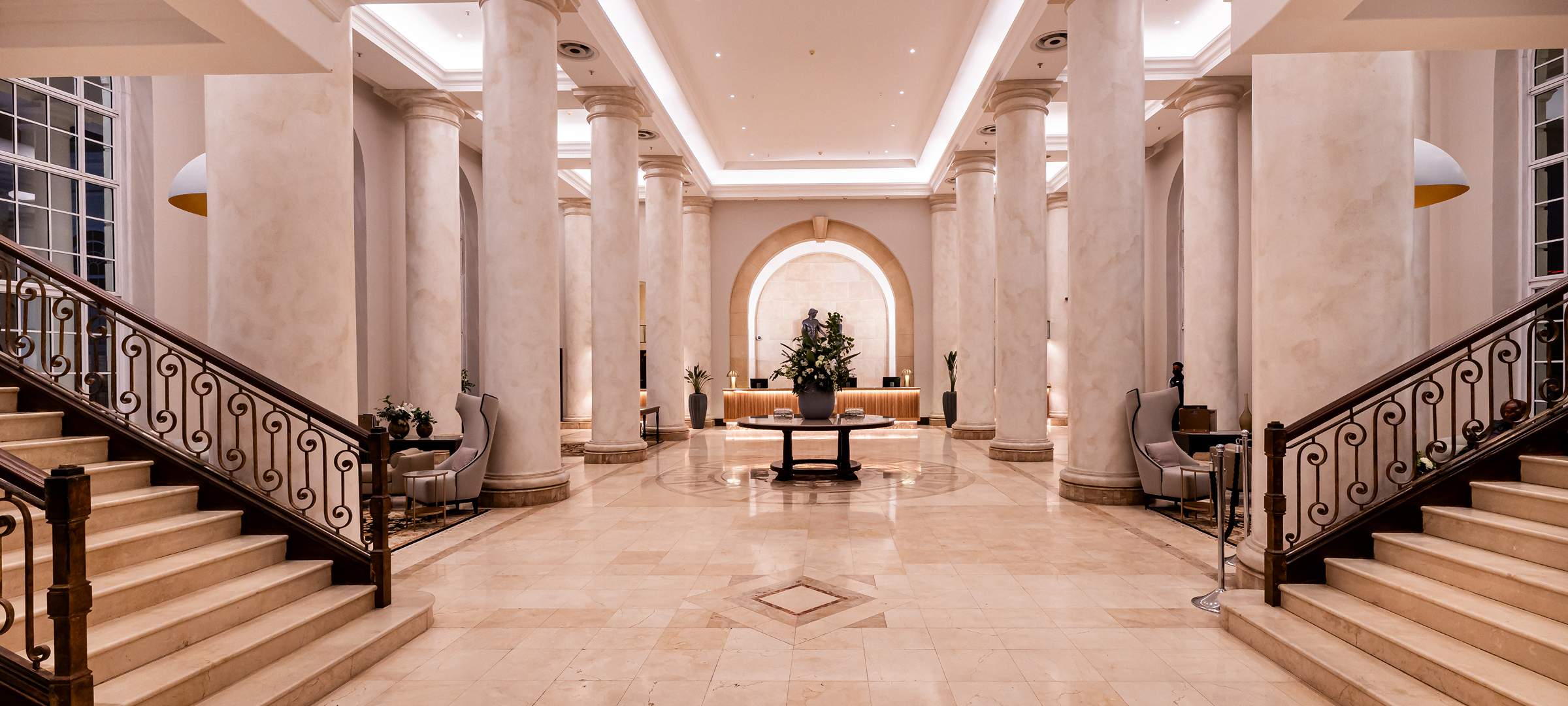 "Luxury marble lobby of The Cullinan Hotel Cape Town with grand columns, ornate balustrades, and arched entryway design"