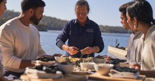 Group sharing oysters outdoors by the water, as part of The Merrimbula Merroir