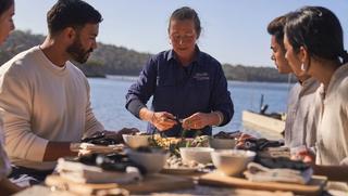 Group sharing oysters outdoors by the water, as part of The Merrimbula Merroir