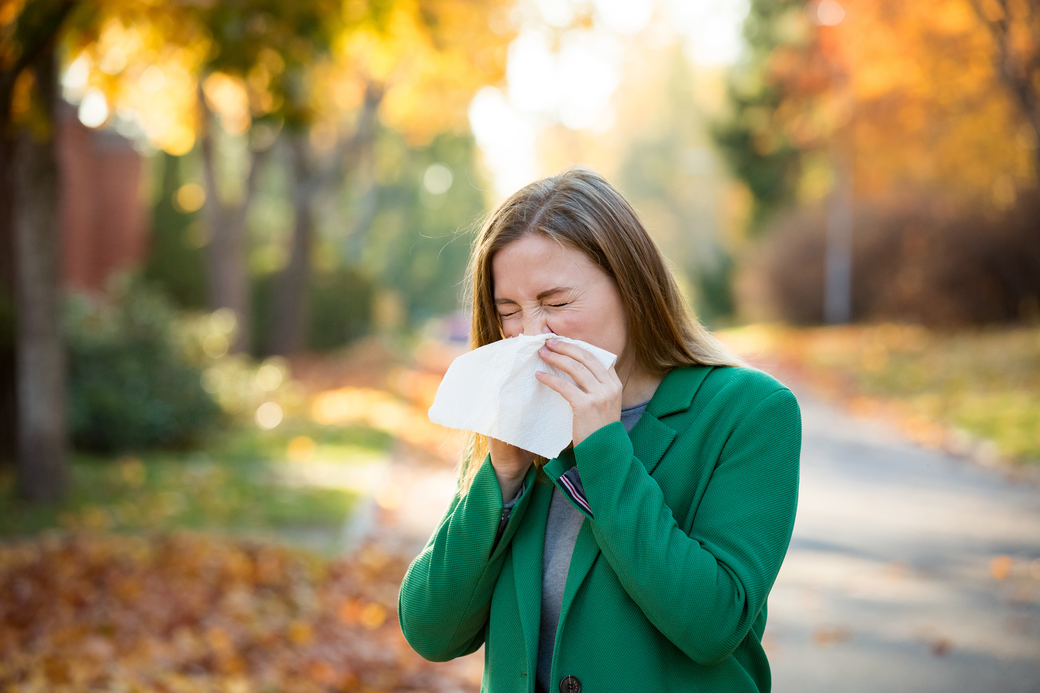 Woman sneezing into tissue from fall allergies | The Allergy Group