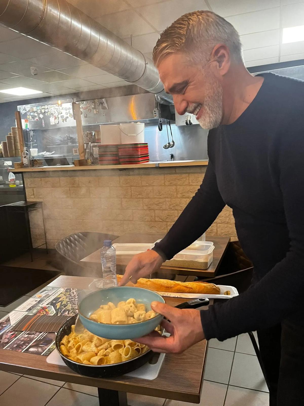 Enzo dresse une assiette de pâtes derrière le comptoir