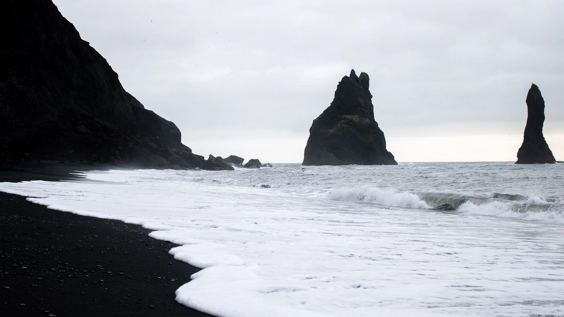 Black sand beach with basalt column formations and rough surf
