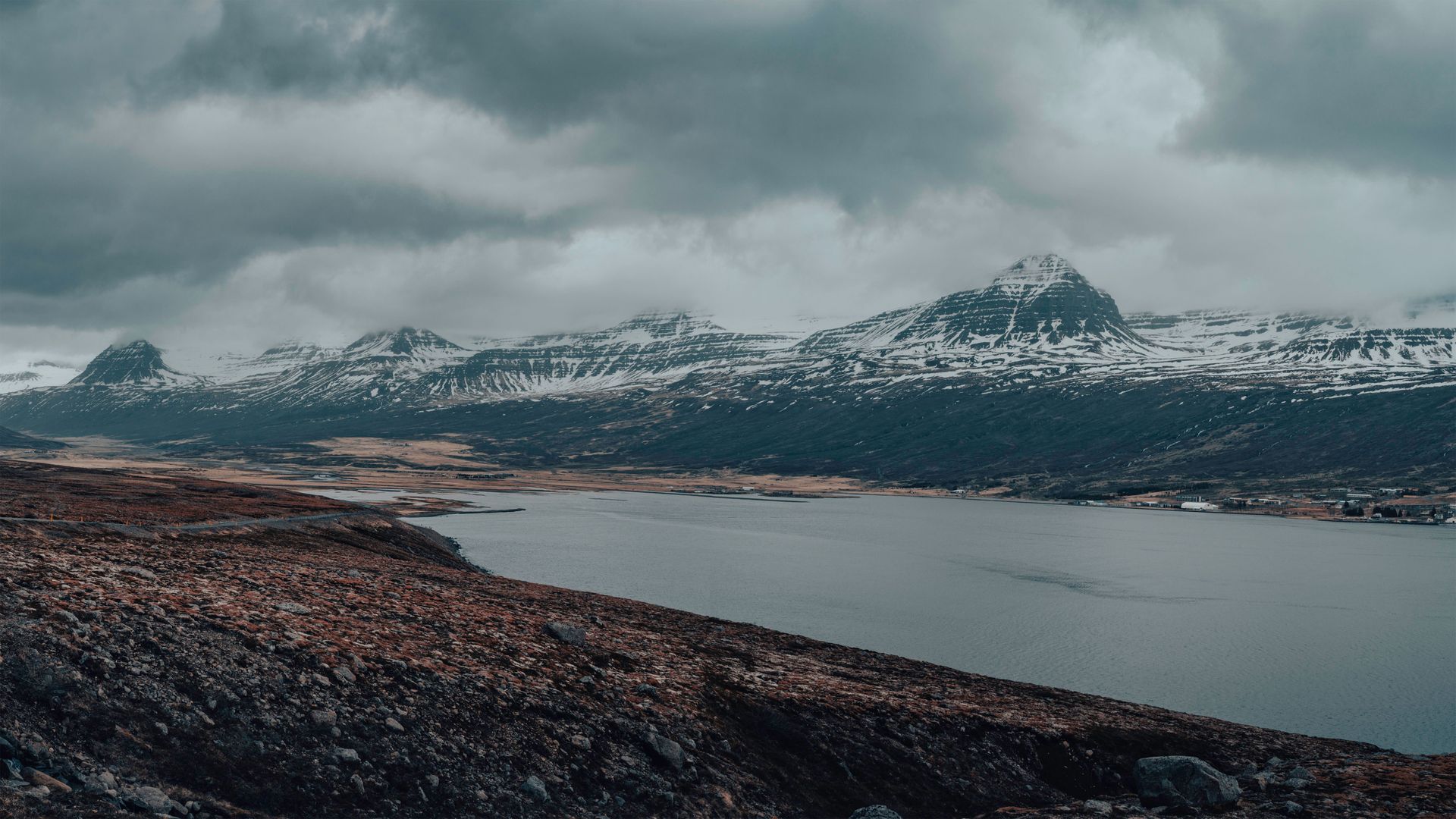 Coastal road curving around a steep fjord in East Iceland