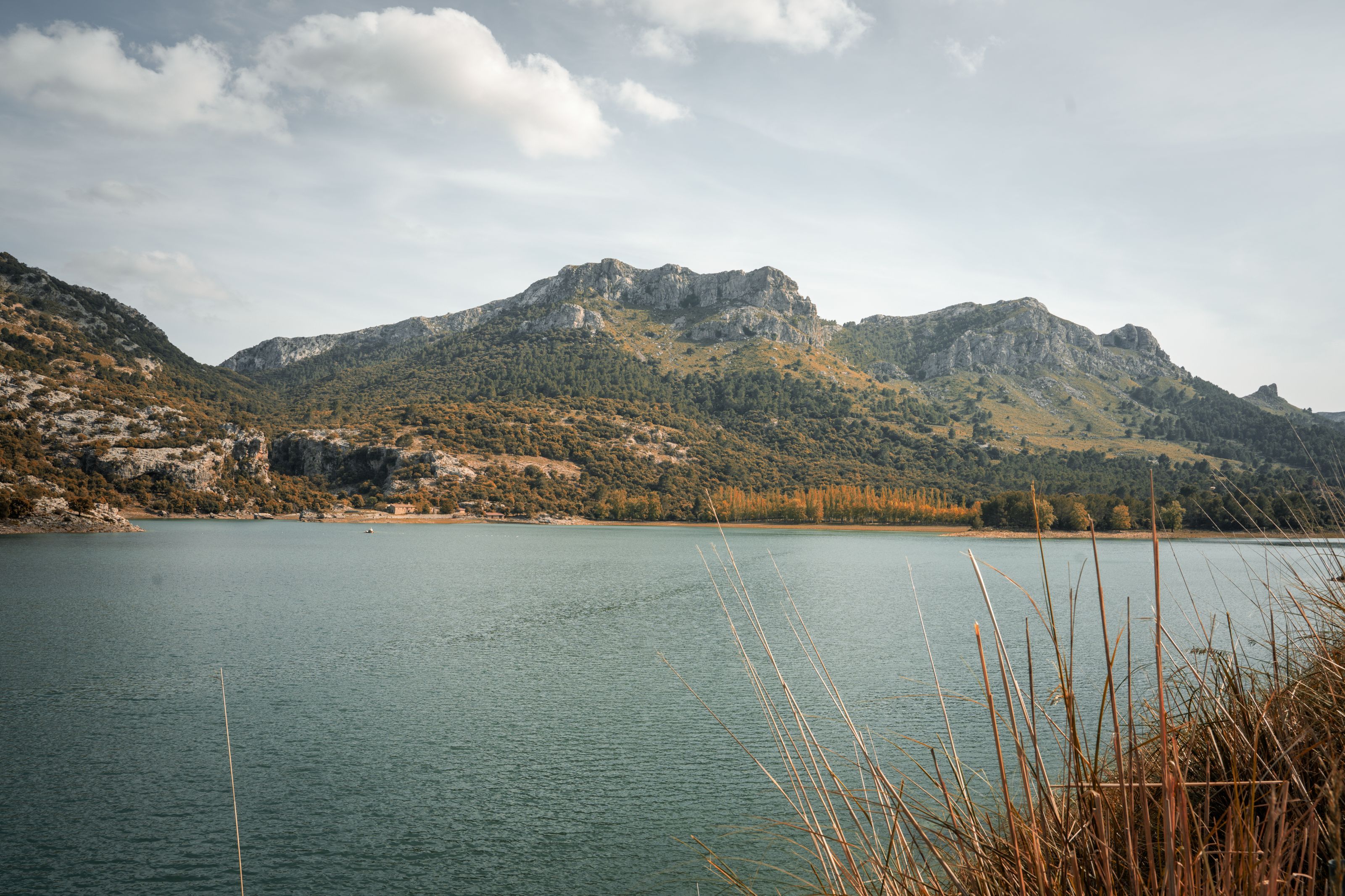 A reservoir below limestone peaks in the Serra de Tramuntana, Mallorca, under a cloudy sky