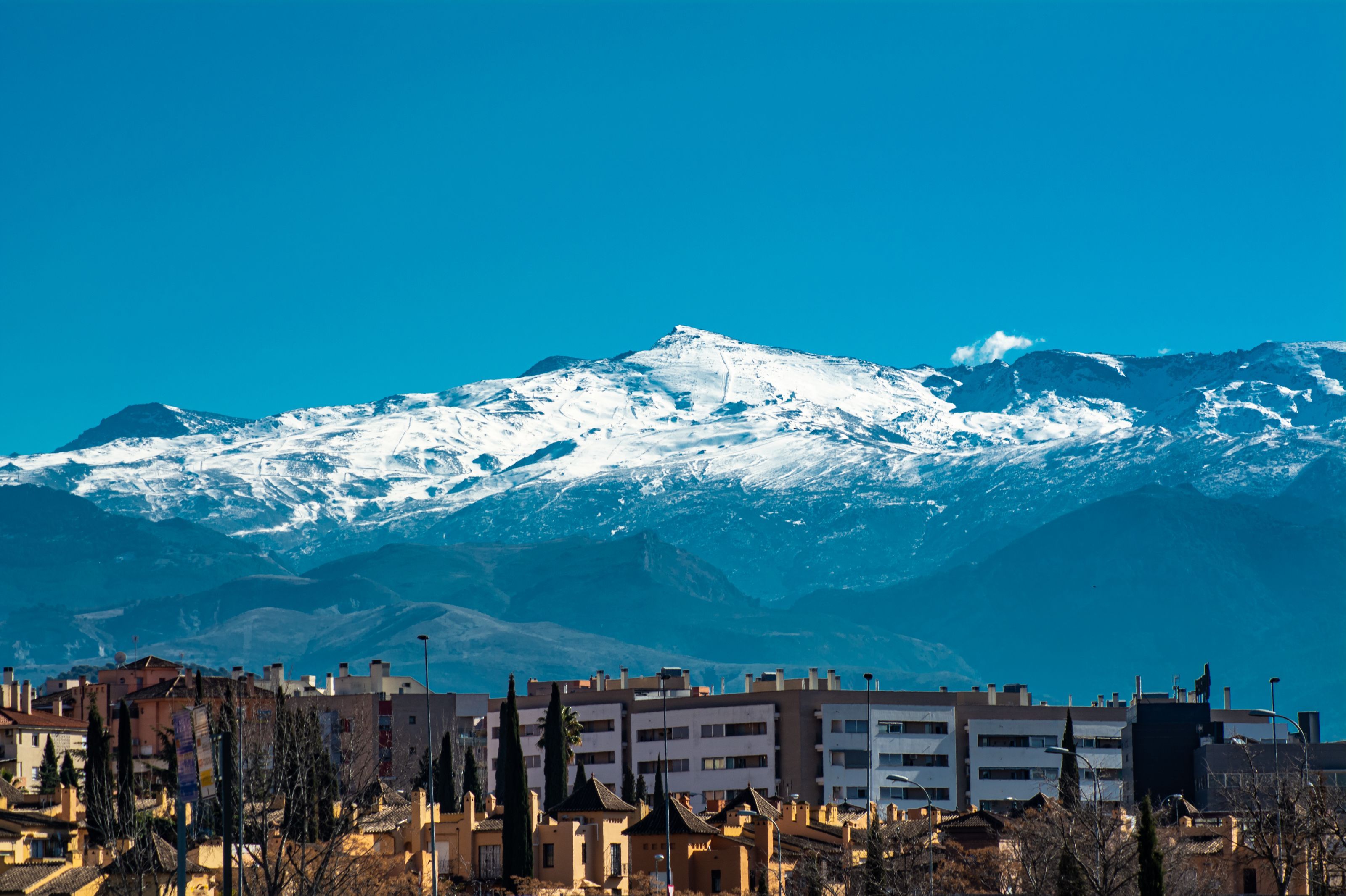Snow-covered peaks of the Sierra Nevada above the rooftops of Granada under a clear sky