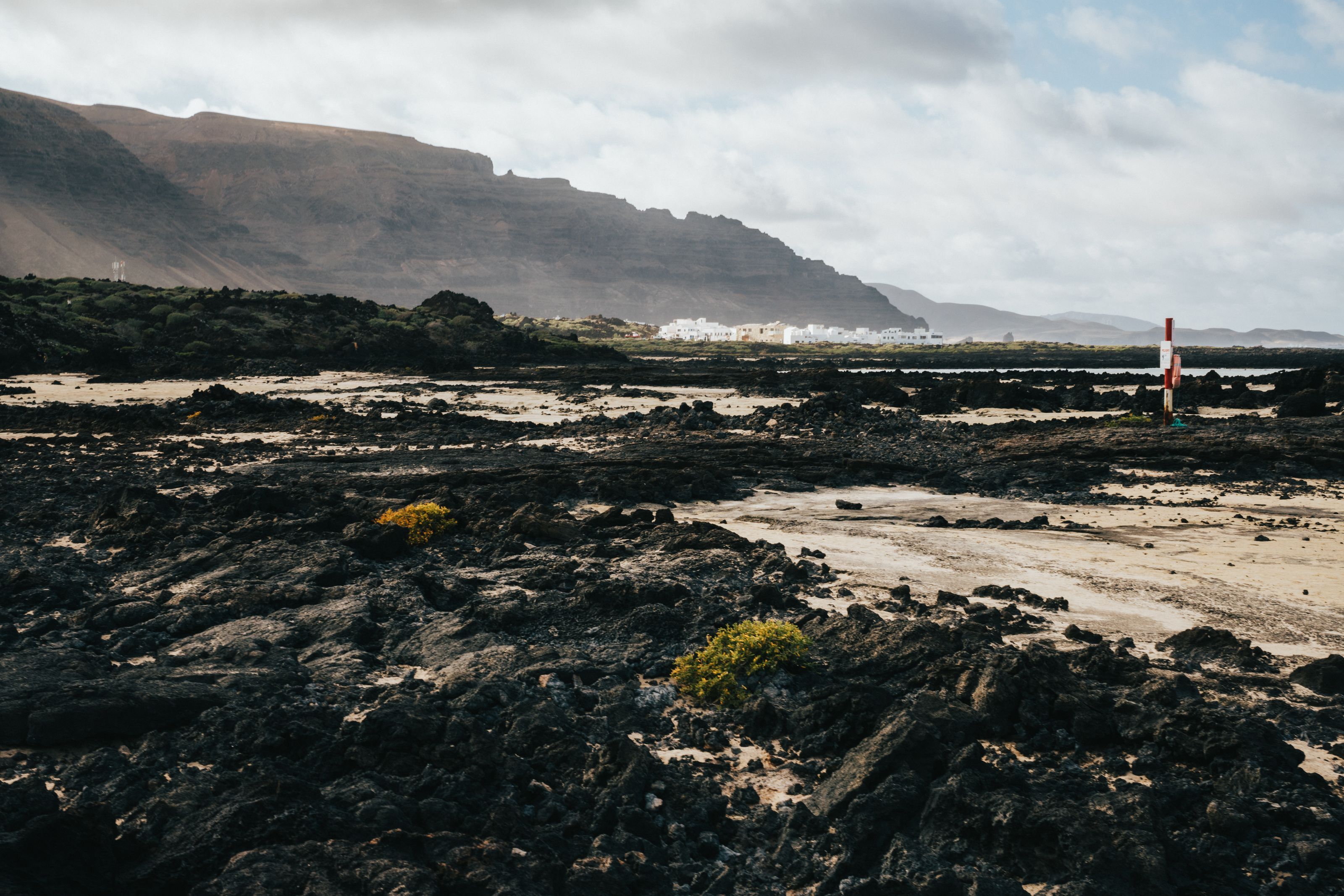 Black lava rock on the coast of Lanzarote with cliffs in the distance