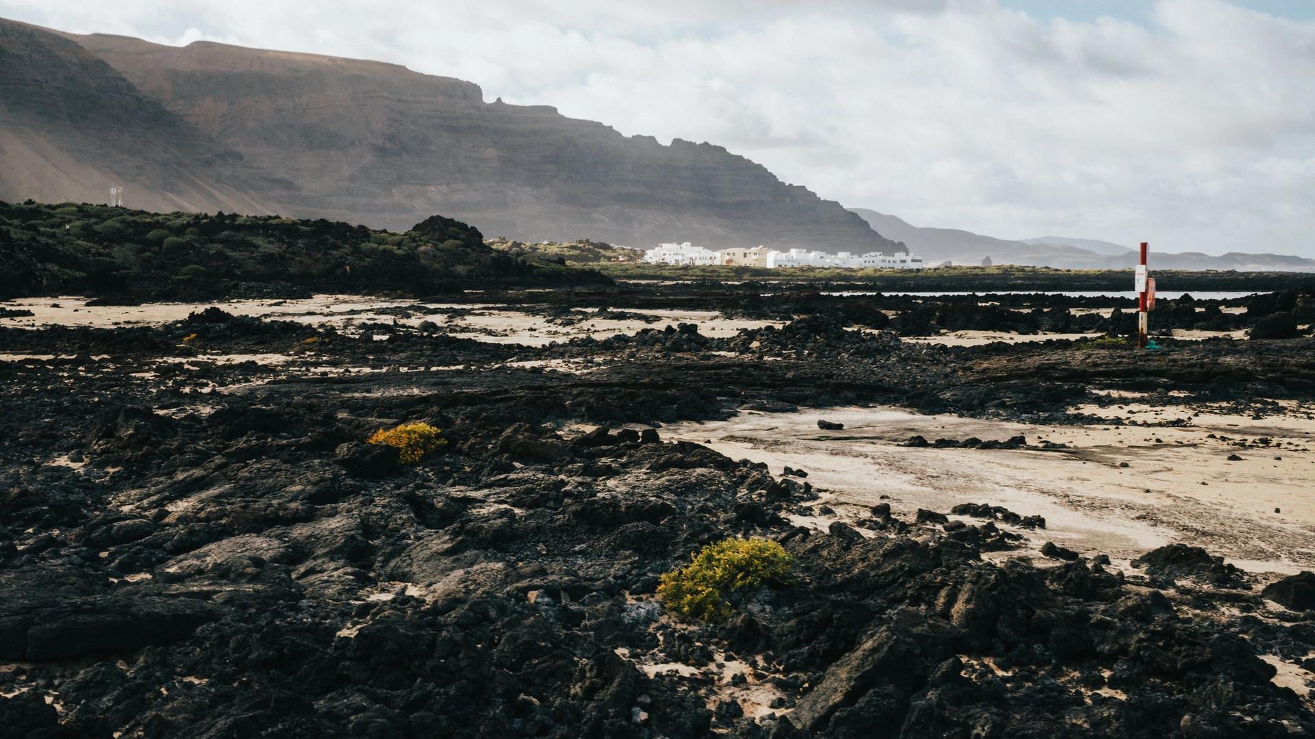 Black lava rock on the coast of Lanzarote with cliffs in the distance