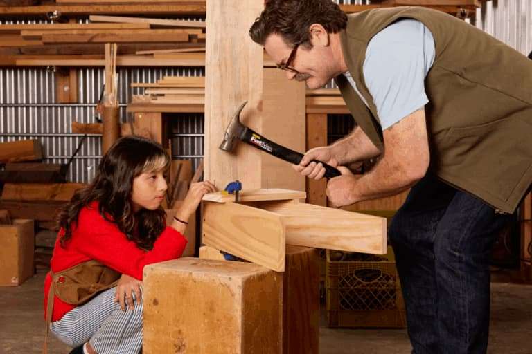 Nick and a child working on a project with hammers and nails.