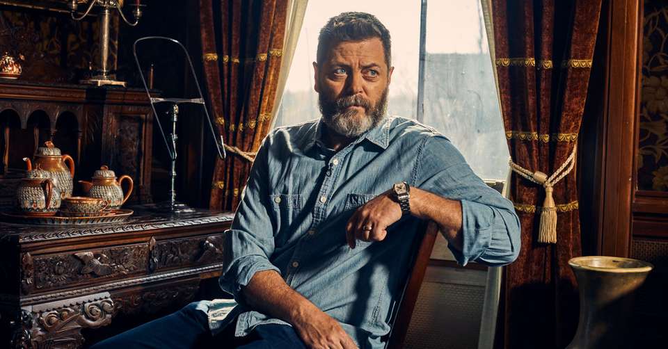 Nick Offerman seated in Mark Twain's house. Wearing blue denim shirt and jeans.