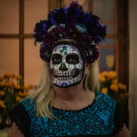 Mujer con ropa tradicional oaxaqueña luciendo un maquillaje de catrina con corona de flores para el Día de Muertos.    A woman wearing traditional Oaxacan clothing and Catrina-style makeup with a flower crown for the Day of the Dead.  