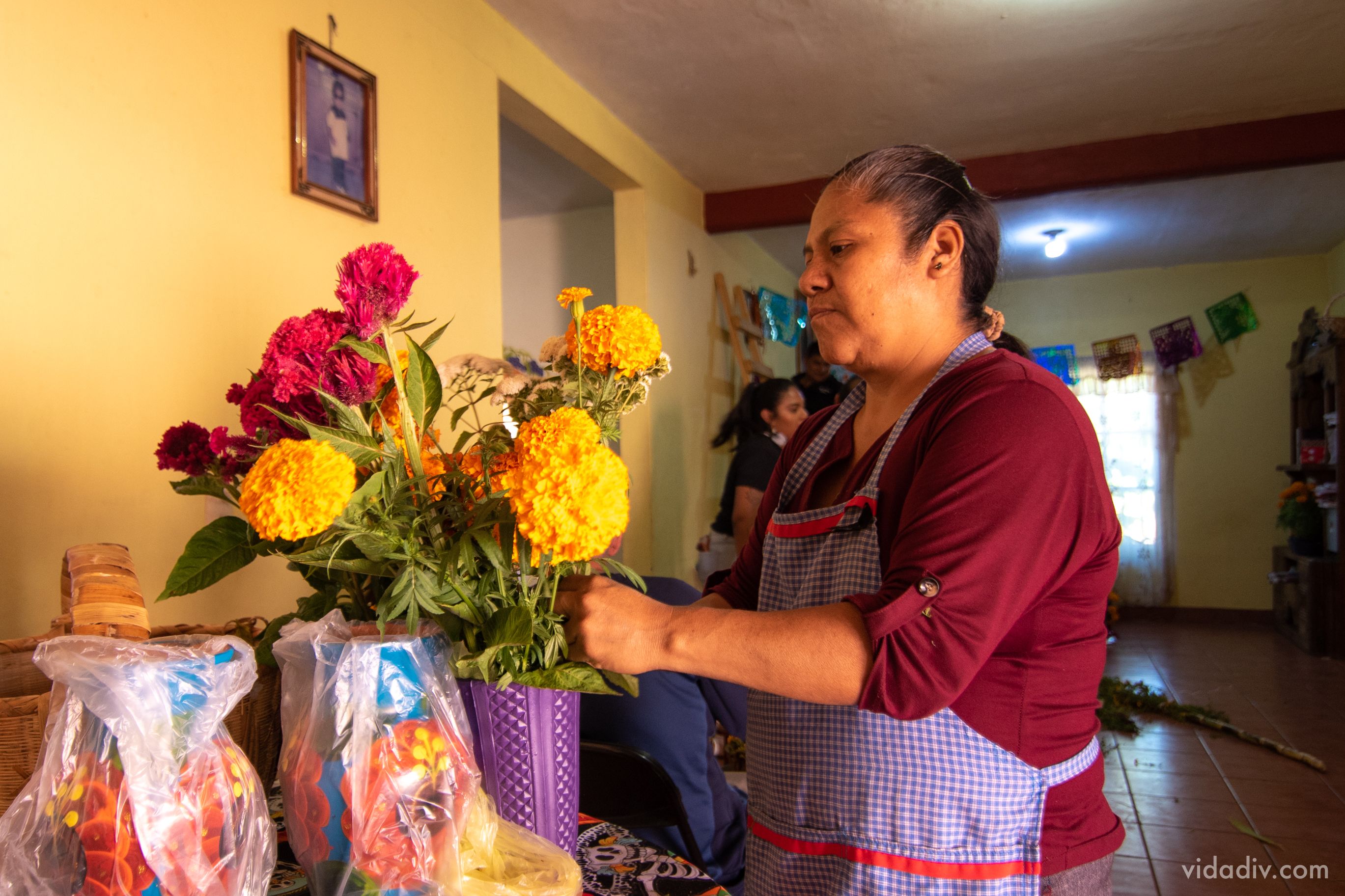 Mujer acomodando flores para una ofrenda tradicional.  A woman arranging flowers for a traditional offering.