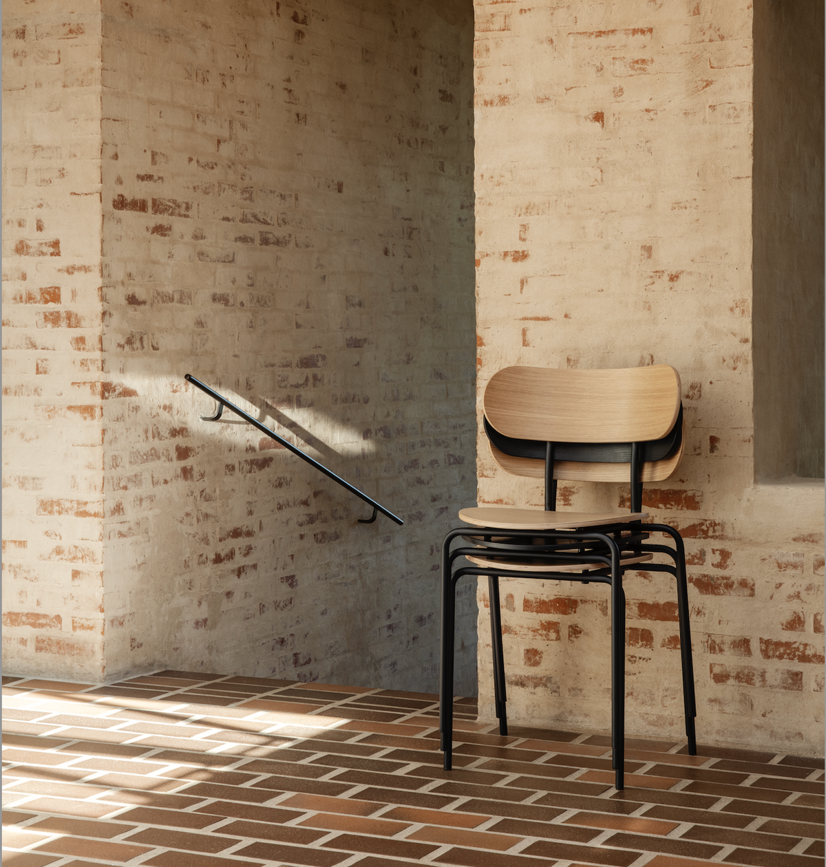 Black and light wood stacked dining chairs on brick floor