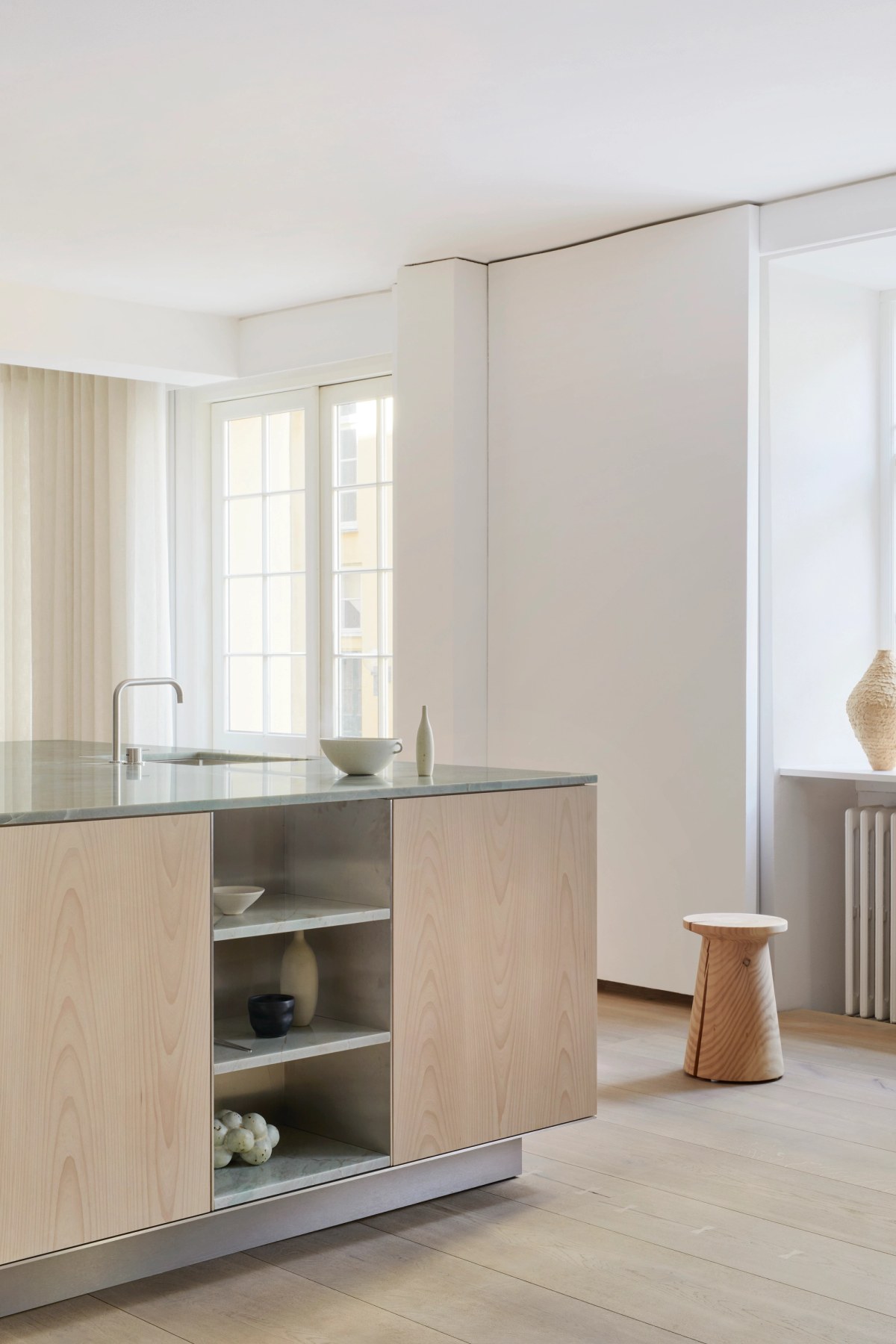Kitchen island in light ash wood and with stone top and decorative objects 