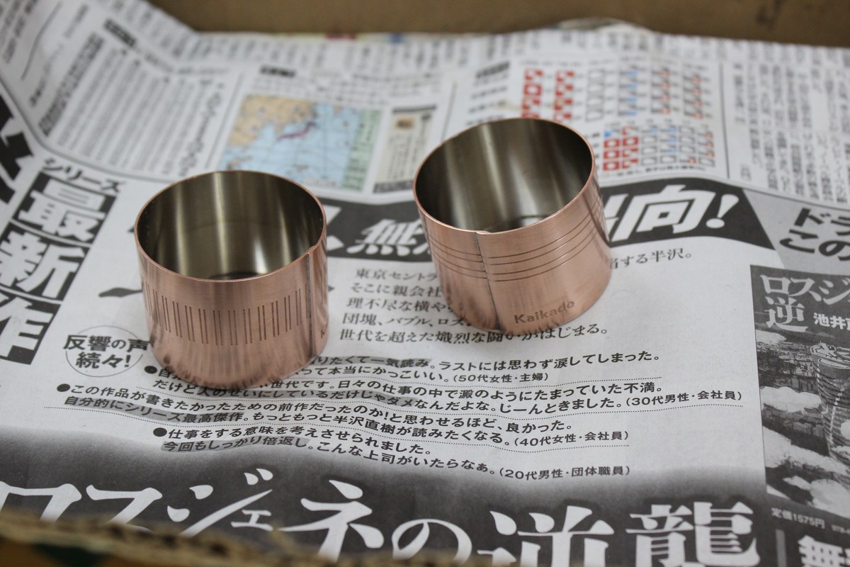 Small sake cups in copper on top of Japanese newspaper